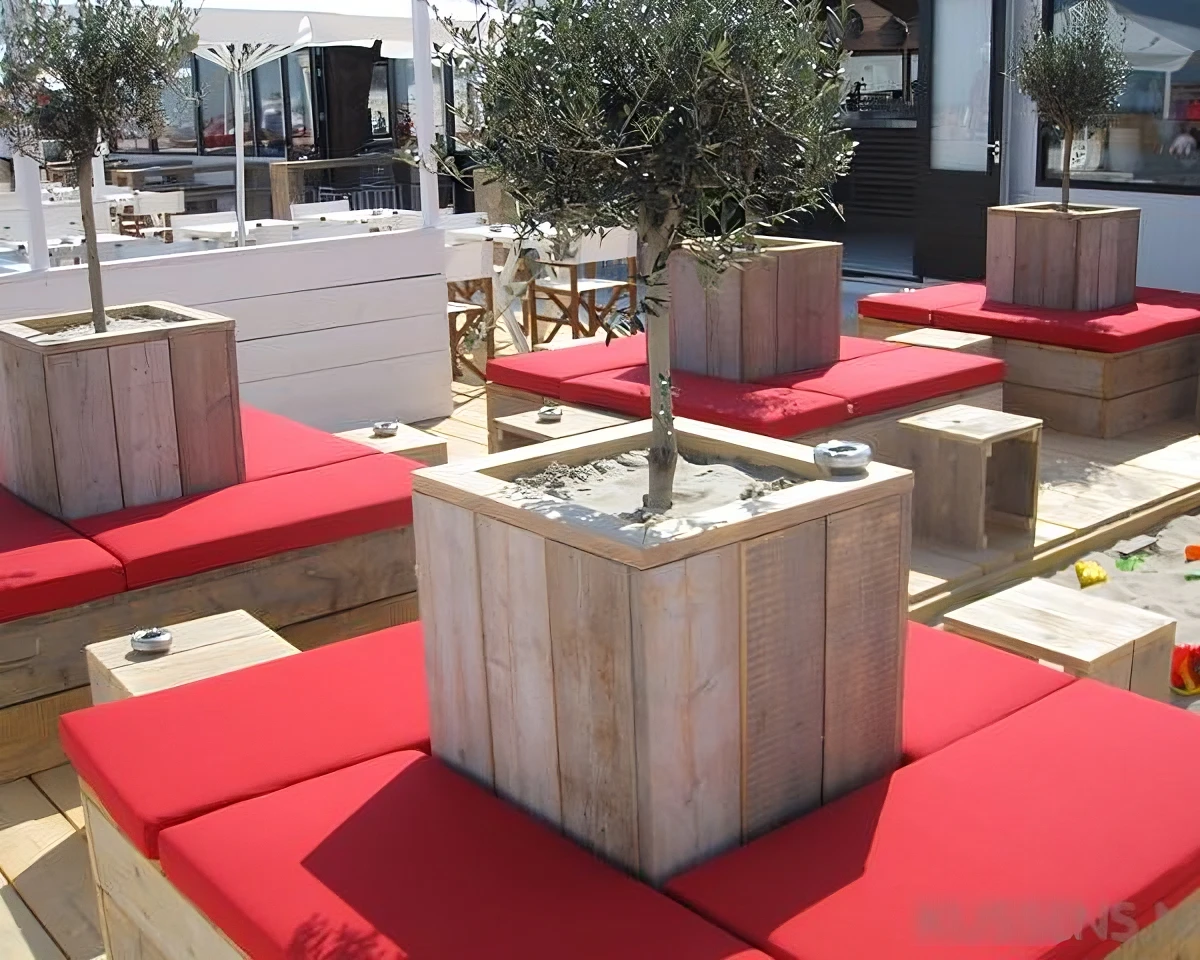Rode horeca kussens op maat rond een steigerhout meubel met planten bank in het midden